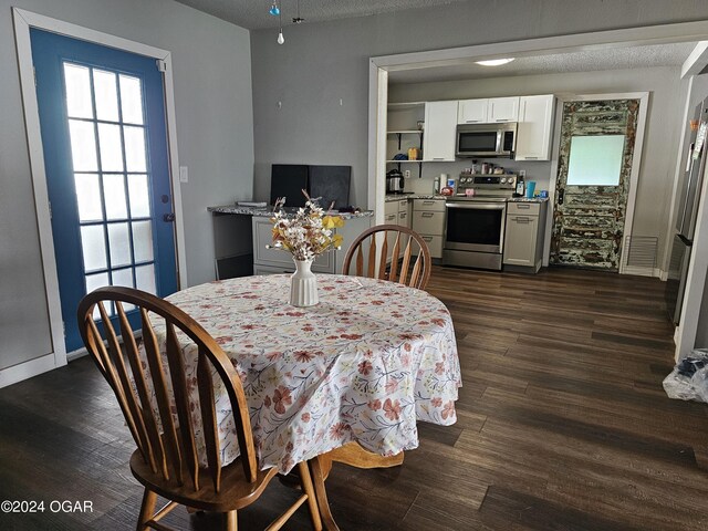 dining area with dark wood-type flooring and a textured ceiling