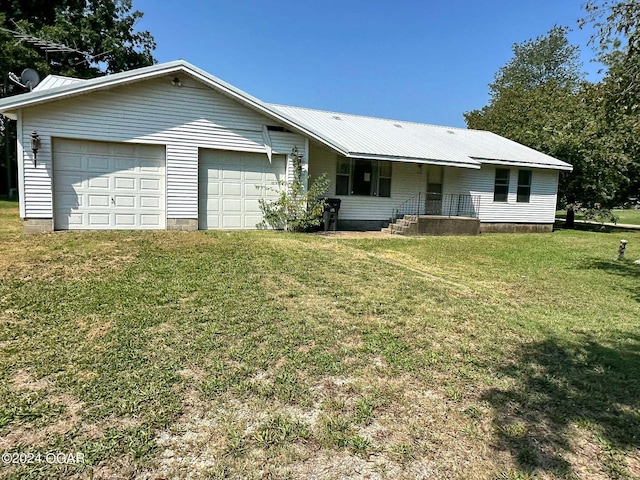 ranch-style house featuring an attached garage, driveway, metal roof, and a front yard