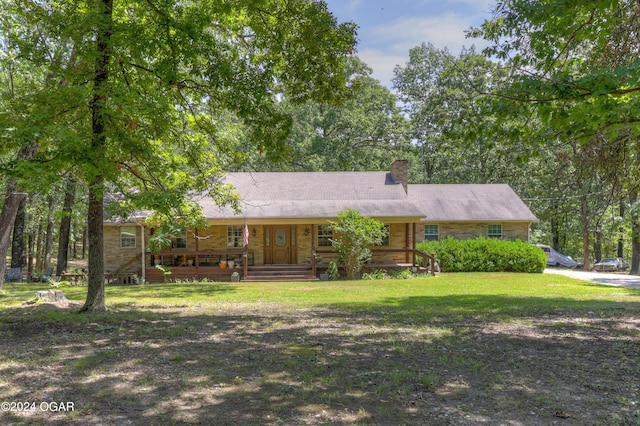 ranch-style house featuring a porch, a chimney, and a front yard