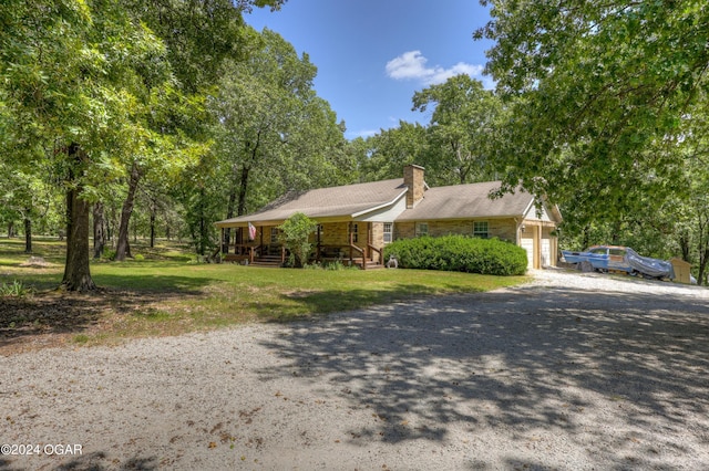 single story home with an attached garage, driveway, a chimney, and a front lawn