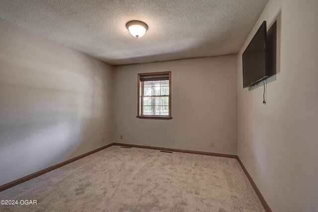 unfurnished room featuring light carpet, visible vents, baseboards, and a textured ceiling