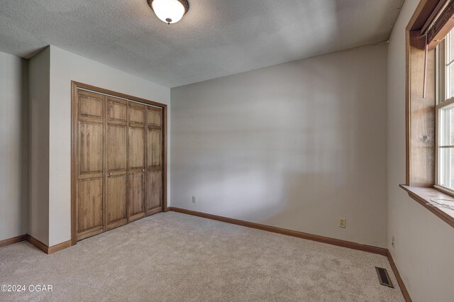 unfurnished bedroom with visible vents, light carpet, and multiple windows