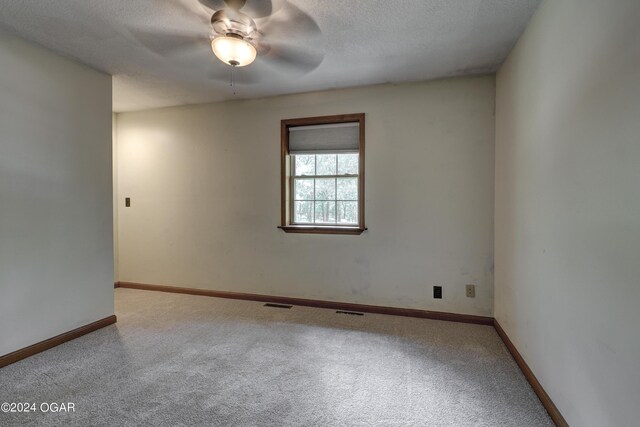 spare room featuring baseboards, carpet, visible vents, and a textured ceiling