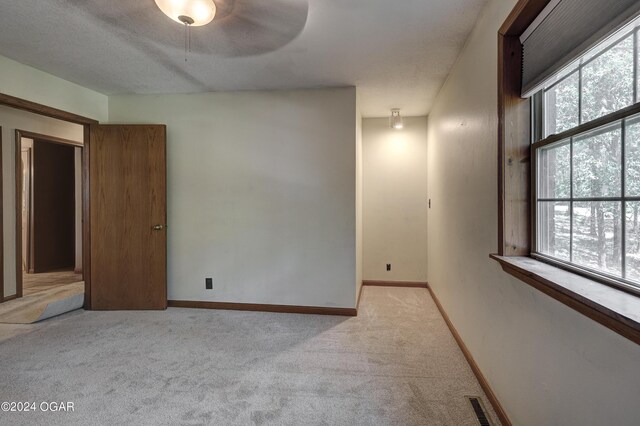 unfurnished room with baseboards, visible vents, a textured ceiling, and light colored carpet