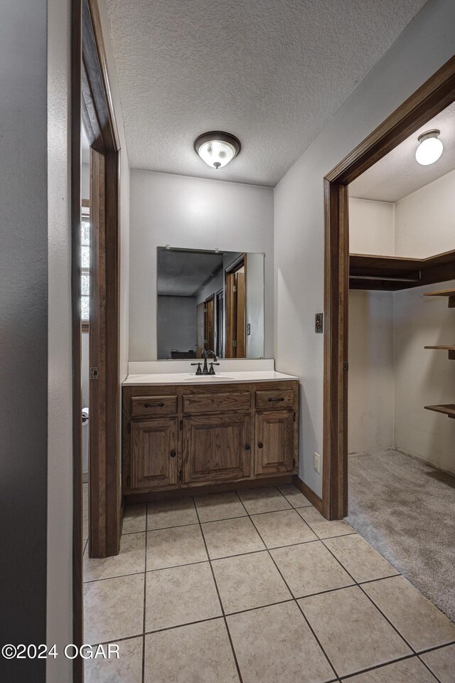 bathroom with tile patterned flooring, a textured ceiling, and vanity