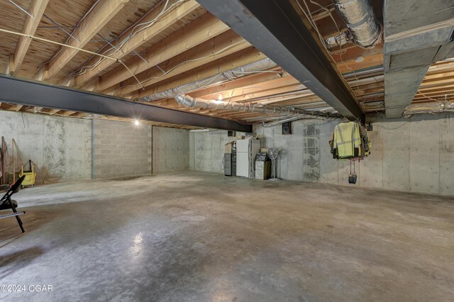 unfinished basement with freestanding refrigerator