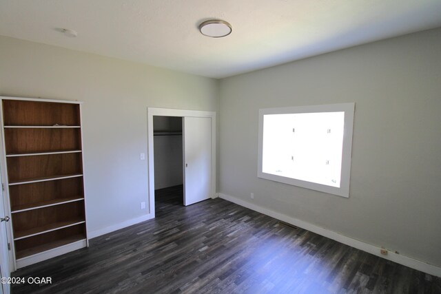 unfurnished bedroom featuring a closet and dark hardwood / wood-style floors