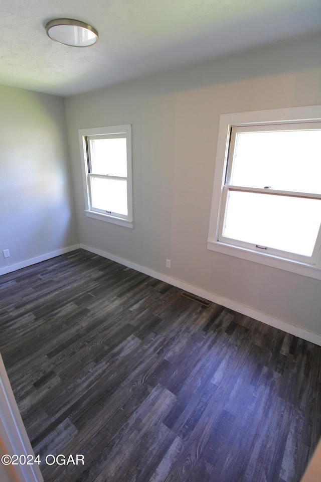 empty room featuring baseboards and dark wood-style flooring