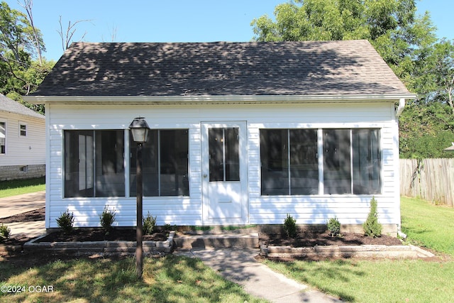 view of front of home with a shingled roof, a front yard, and fence