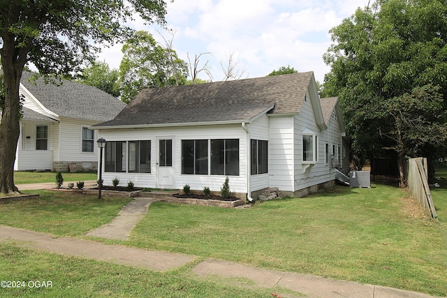 view of front of property featuring entry steps, central AC unit, roof with shingles, and a front yard