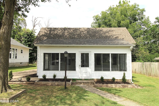 view of front of property with a shingled roof, entry steps, fence, and a front lawn