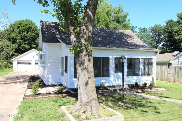 view of front of property featuring a garage, a front yard, and an outdoor structure