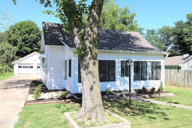 view of front of home featuring an outbuilding, roof with shingles, and a front yard