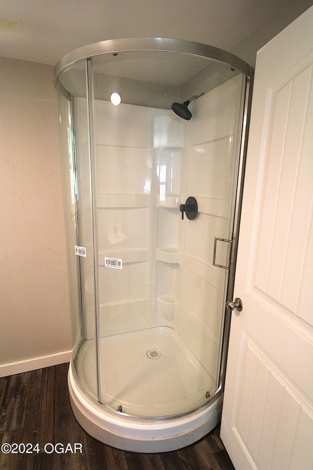 full bathroom with baseboards, wood finished floors, and a shower stall