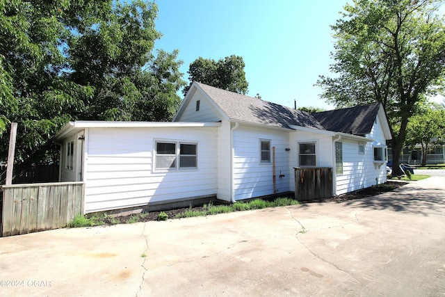 back of property with fence and roof with shingles