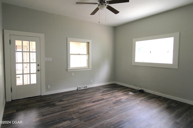 unfurnished room featuring a ceiling fan, dark wood-style flooring, visible vents, and baseboards