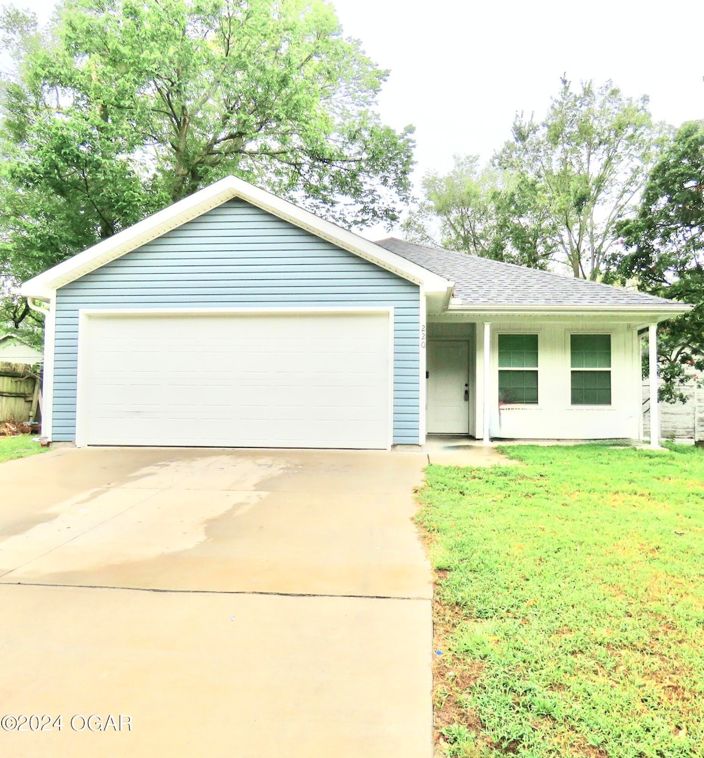 single story home with a garage and a front lawn