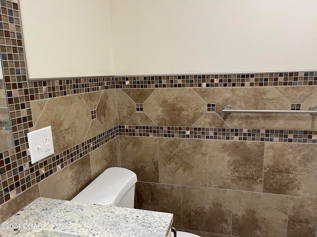 bathroom featuring tile walls, toilet, and vanity