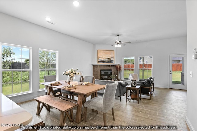 dining room with ceiling fan, light hardwood / wood-style floors, and a brick fireplace