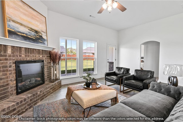 living room featuring ceiling fan and a brick fireplace