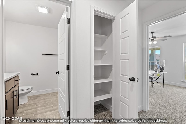 bathroom featuring toilet, ceiling fan, and vanity