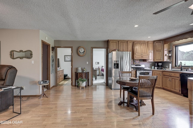 kitchen featuring appliances with stainless steel finishes, a textured ceiling, sink, and light hardwood / wood-style floors