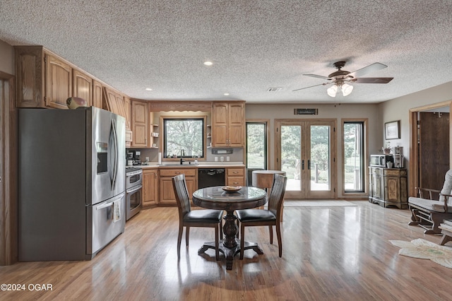 kitchen with a wealth of natural light, stainless steel appliances, light hardwood / wood-style floors, and french doors