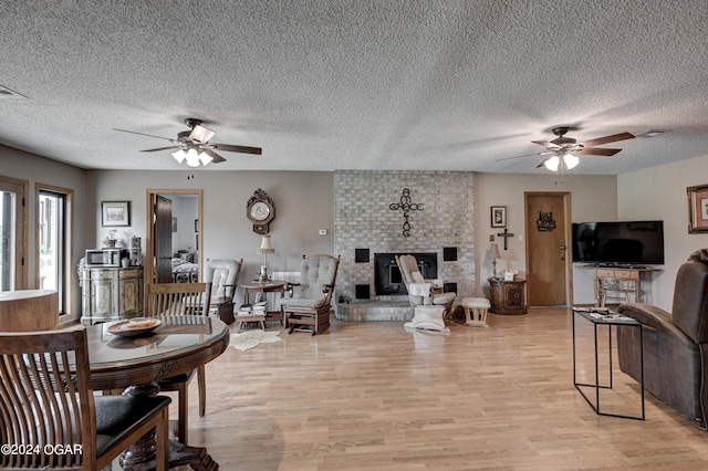 living room featuring a textured ceiling, light hardwood / wood-style flooring, and ceiling fan