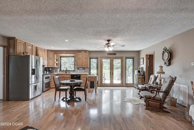 kitchen with a textured ceiling, french doors, light hardwood / wood-style floors, stainless steel appliances, and ceiling fan