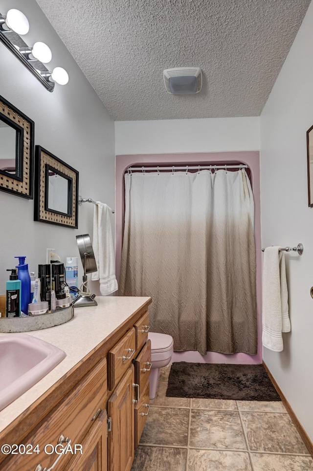 bathroom with a textured ceiling, vanity, curtained shower, toilet, and tile patterned floors