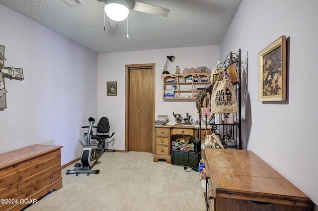 carpeted home office featuring a textured ceiling and ceiling fan