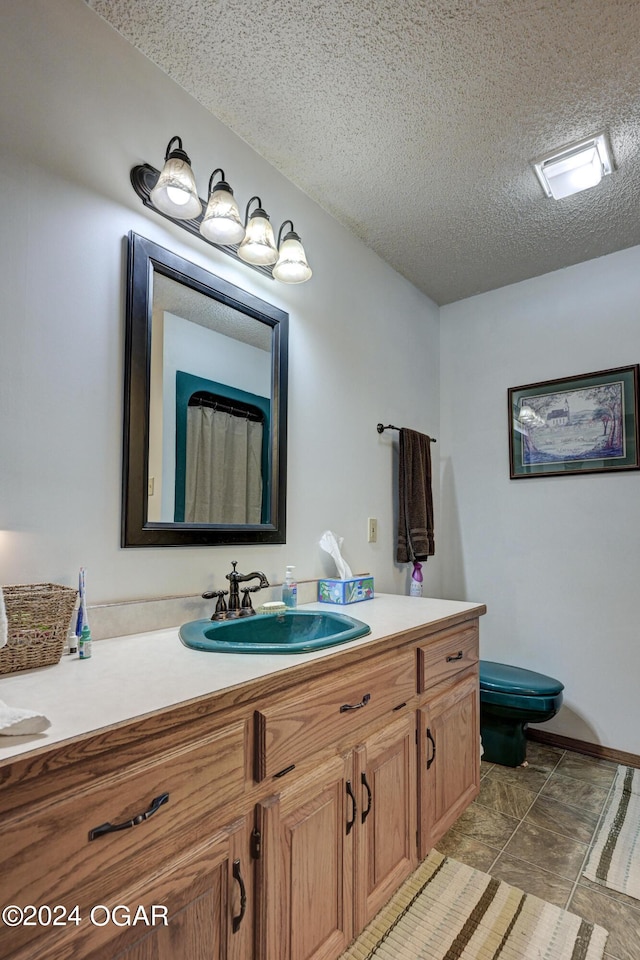 bathroom featuring vanity, toilet, a textured ceiling, and tile patterned flooring