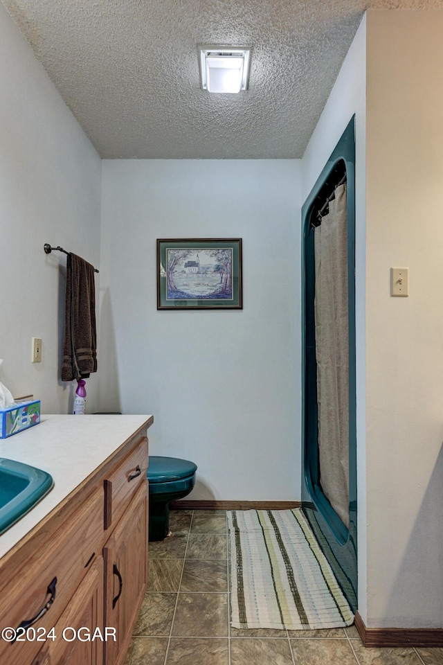 bathroom with a textured ceiling, vanity, curtained shower, tile patterned flooring, and toilet