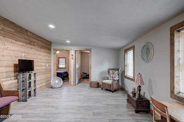 sitting room featuring vaulted ceiling, wooden walls, and light hardwood / wood-style floors