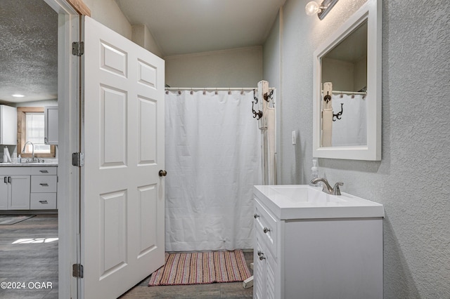 bathroom featuring vanity, vaulted ceiling, and wood-type flooring