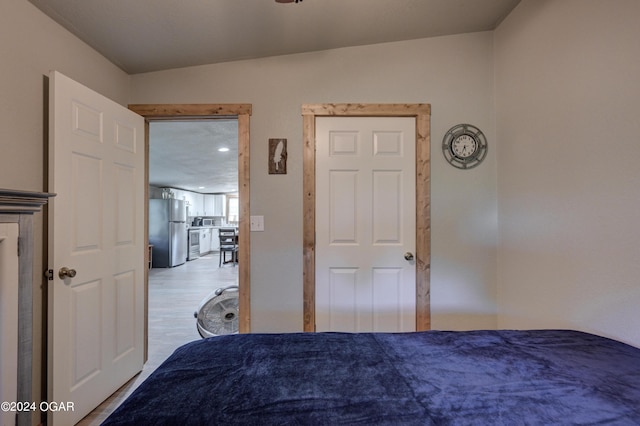 unfurnished bedroom featuring stainless steel fridge, lofted ceiling, and light hardwood / wood-style flooring