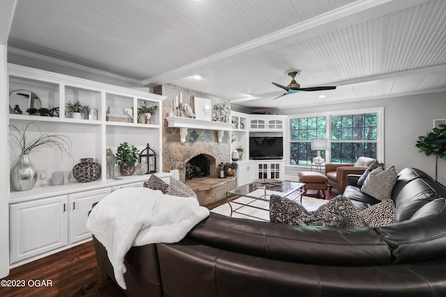 living area featuring a stone fireplace, dark wood-type flooring, a ceiling fan, beamed ceiling, and crown molding