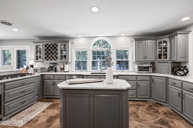 kitchen with recessed lighting, glass insert cabinets, stainless steel appliances, and gray cabinetry