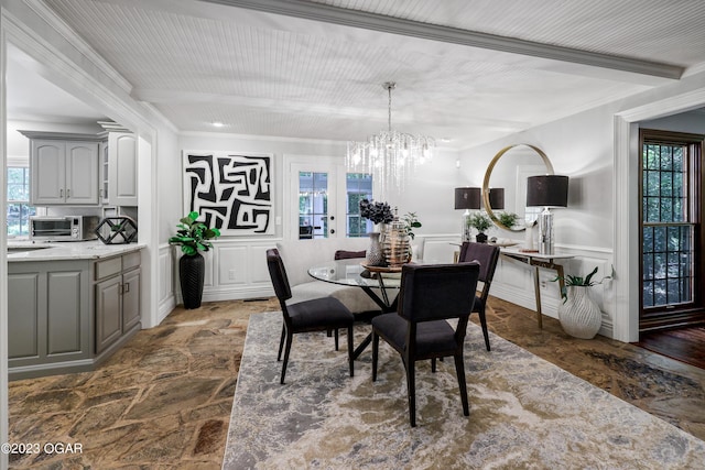 dining space featuring ornamental molding, a notable chandelier, a decorative wall, and beamed ceiling