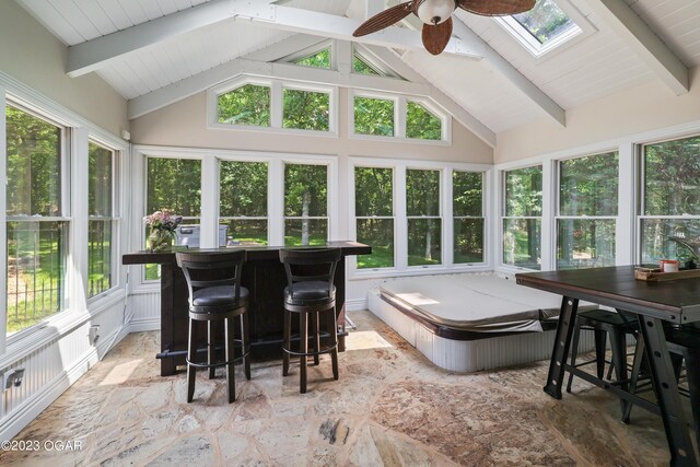 sunroom / solarium with ceiling fan and vaulted ceiling with skylight