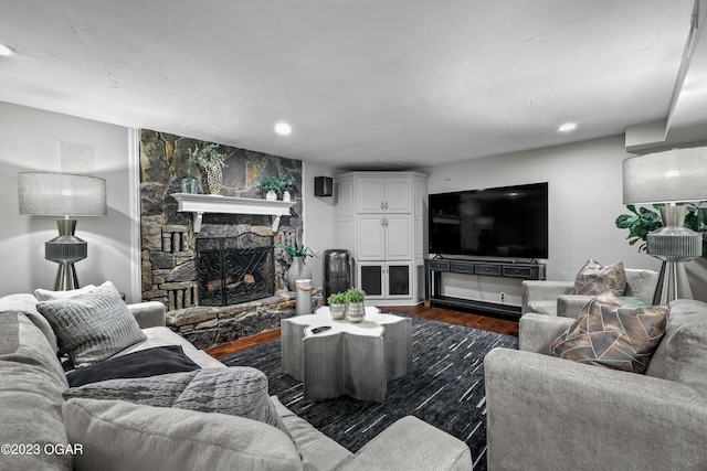 living room with dark wood-type flooring and a stone fireplace