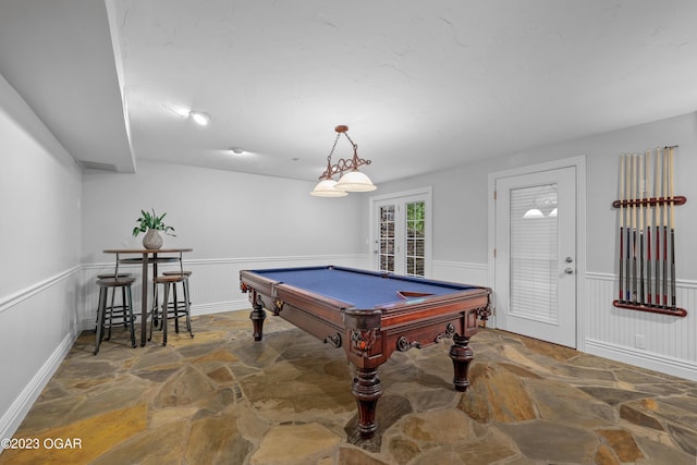 game room with stone floors, a wainscoted wall, and billiards