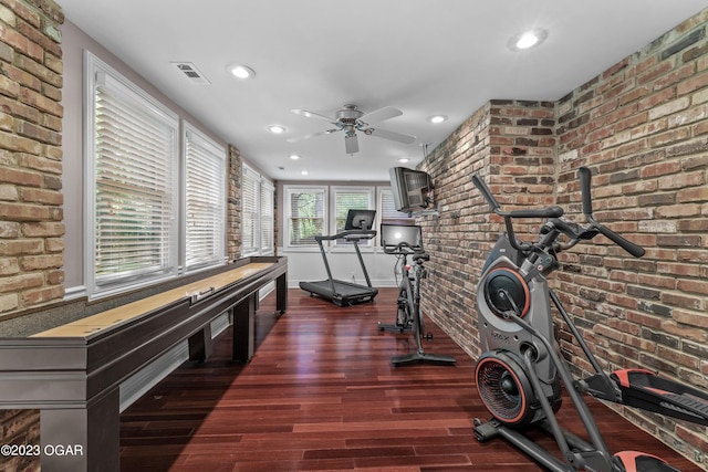 workout area featuring ceiling fan and brick wall