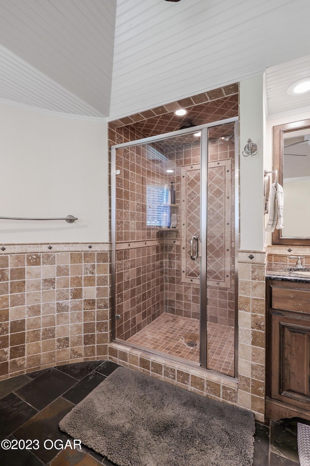 bathroom with a wainscoted wall, a shower stall, and tile walls