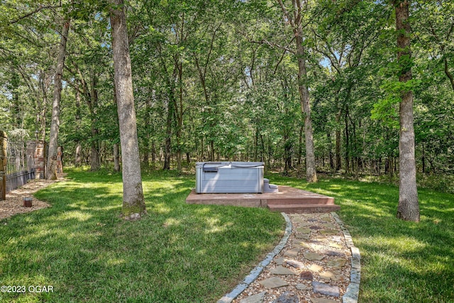 view of yard featuring fence, a hot tub, and a wooded view