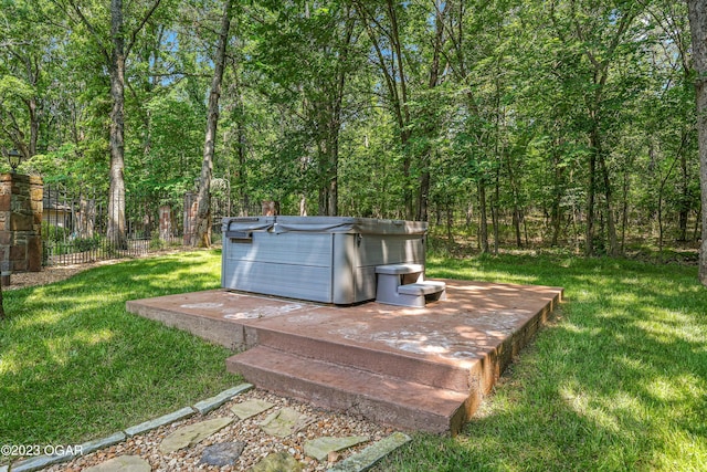 details featuring a forest view, a hot tub, and fence