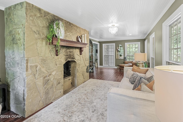 living area featuring crown molding, a stone fireplace, and wood finished floors