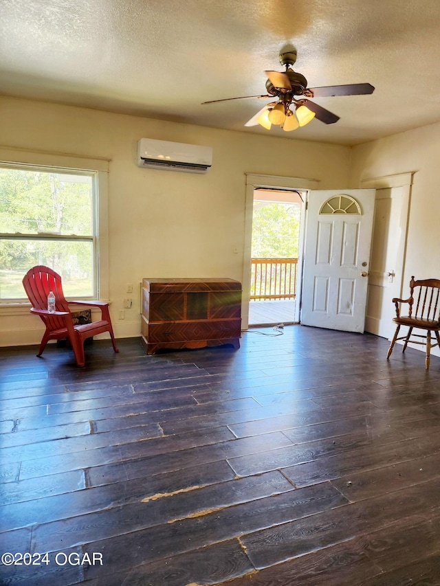 living area featuring ceiling fan, a textured ceiling, a wall mounted air conditioner, and dark hardwood / wood-style flooring