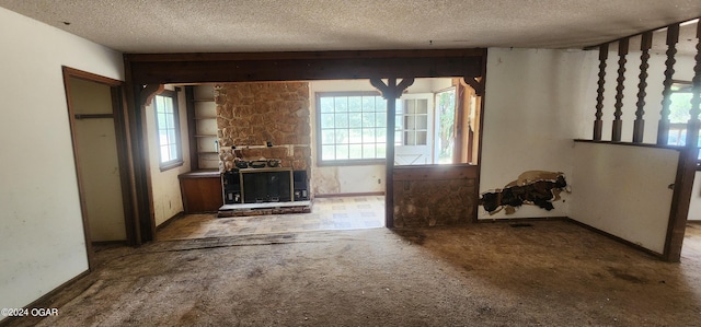 unfurnished living room with carpet floors, a fireplace, a textured ceiling, and a healthy amount of sunlight