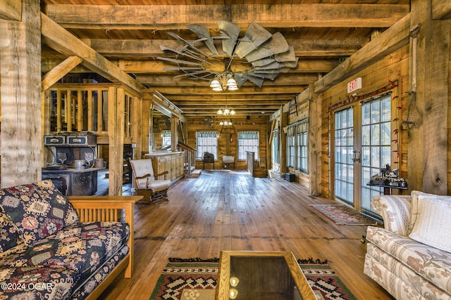 unfurnished living room featuring wood-type flooring, beam ceiling, wood walls, and ceiling fan